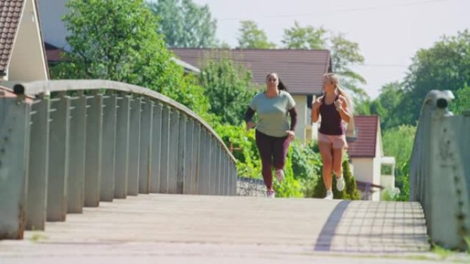 女私人教练与超重的女客户一起在城市的一座桥上奔跑