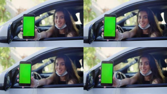 女司机使用手机上的数字疫苗护照应用程序。探出车窗。屏幕上的色度键