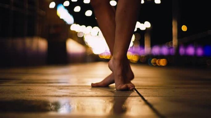 年轻女子在潮湿的城市街道上表演自由式舞蹈。赤脚特写