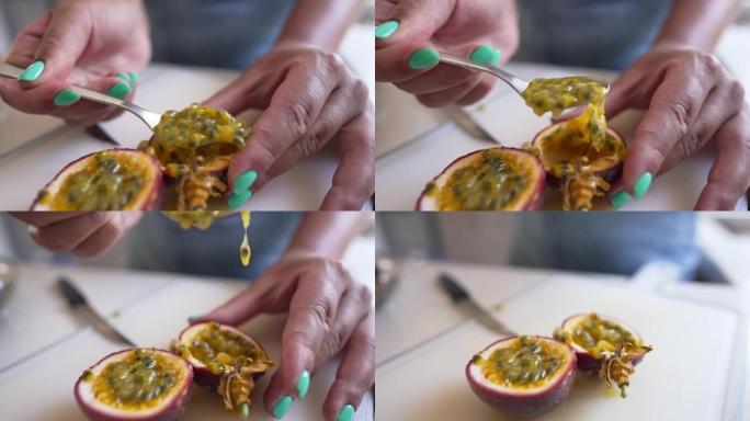 特写女性手与修指甲采取百香果在慢动作用勺子。无法辨认的苗条年轻白人妇女在室内吃美味可口的维生素水果。