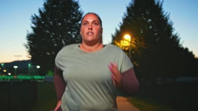 TS超重的女人在黄昏时在城市的公园里跑步