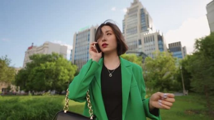 自信而成功的韩国女商人独自行走，用手机聊天，肖像