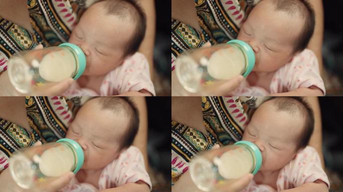 慈爱的母亲在家用奶瓶喂养新生的儿子