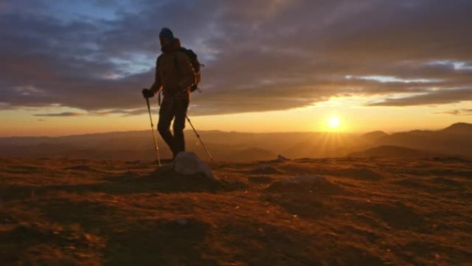 空中SLO MO男徒步旅行者日落时在山顶行走