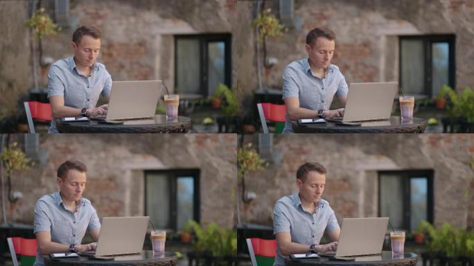 戴眼镜的自由职业者在咖啡馆勤奋地在笔记本电脑上工作。男子在键盘上打字并在咖啡店的互联网上搜索新工作