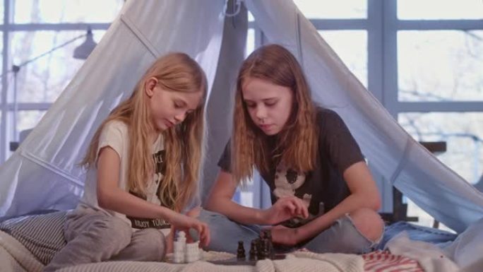 两姐妹在舒适的天篷床上下棋。失败后的安慰