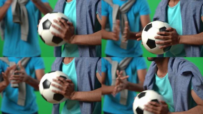 激动的中东足球迷手中的球在绿屏上与朋友一起欢呼。无法识别的年轻人在chromakey背景下支持国家队