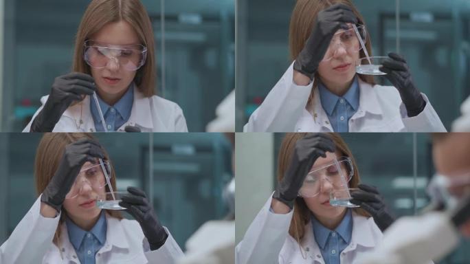 化学学院的学生在课堂上做实际工作，戴着防护眼镜和白色长袍的年轻女子肖像
