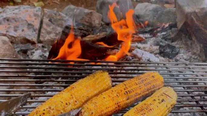 POV人在篝火上的烤架上翻玉米