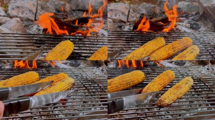 POV人在篝火上的烤架上翻玉米
