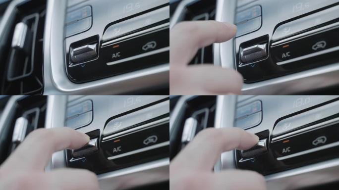 用手调节车内的空调控制按钮。气候控制按钮是银色的。自动模式下的气候系统。男子调节车内的气候控制