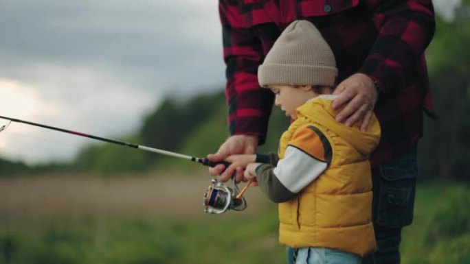 好奇的小男孩正在学习在湖中钓竿捕鱼，祖父正在教孙子