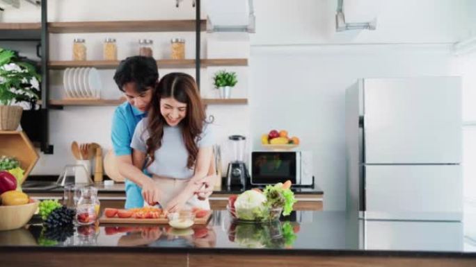 一对幸福的夫妇在家庭厨房里用有趣的时刻准备和烹饪健康的蔬菜沙拉。为年轻夫妇在良好的心情和健康的关系中