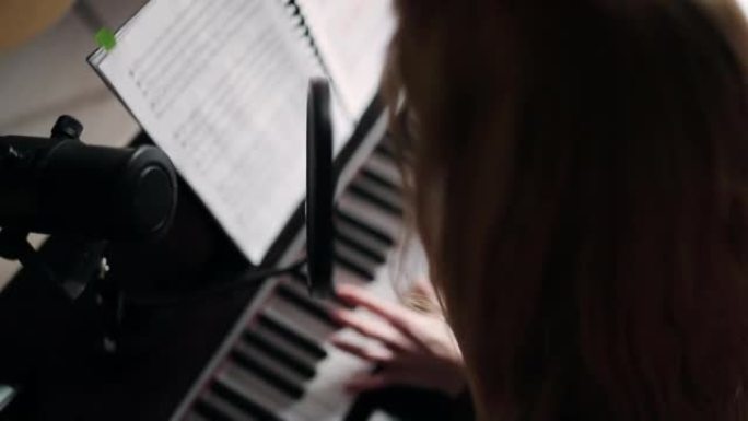 女人弹钢琴，对着麦克风唱圣诞颂歌。音乐录音和歌唱课在家