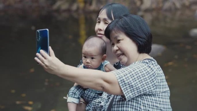 幸福的家庭在瀑布旅行并使用智能手机拍照