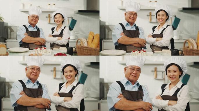 两个快乐的厨师在他的厨房里交叉站着的肖像。