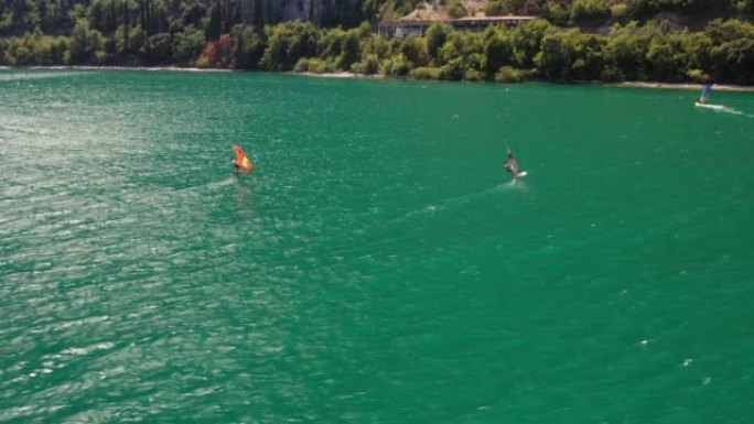 在刮风的晴天，一群机翼冲浪者在湖上的空中无人机拍摄