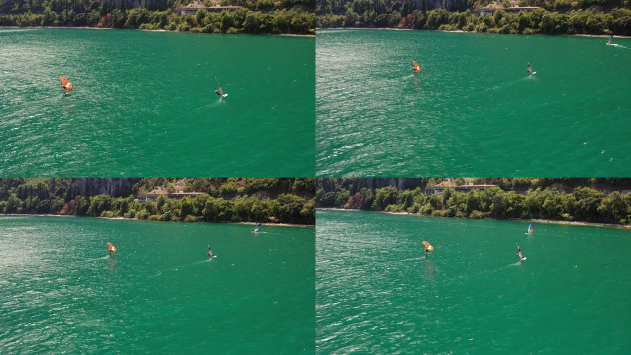 在刮风的晴天，一群机翼冲浪者在湖上的空中无人机拍摄