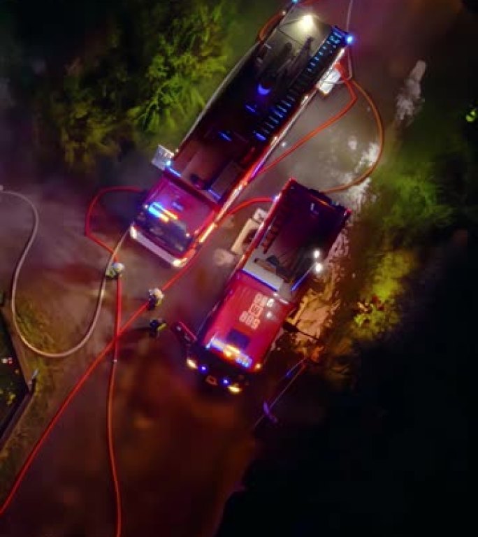 一群消防员夜间灭火的无人机飞行视点。英雄救人垂直视频