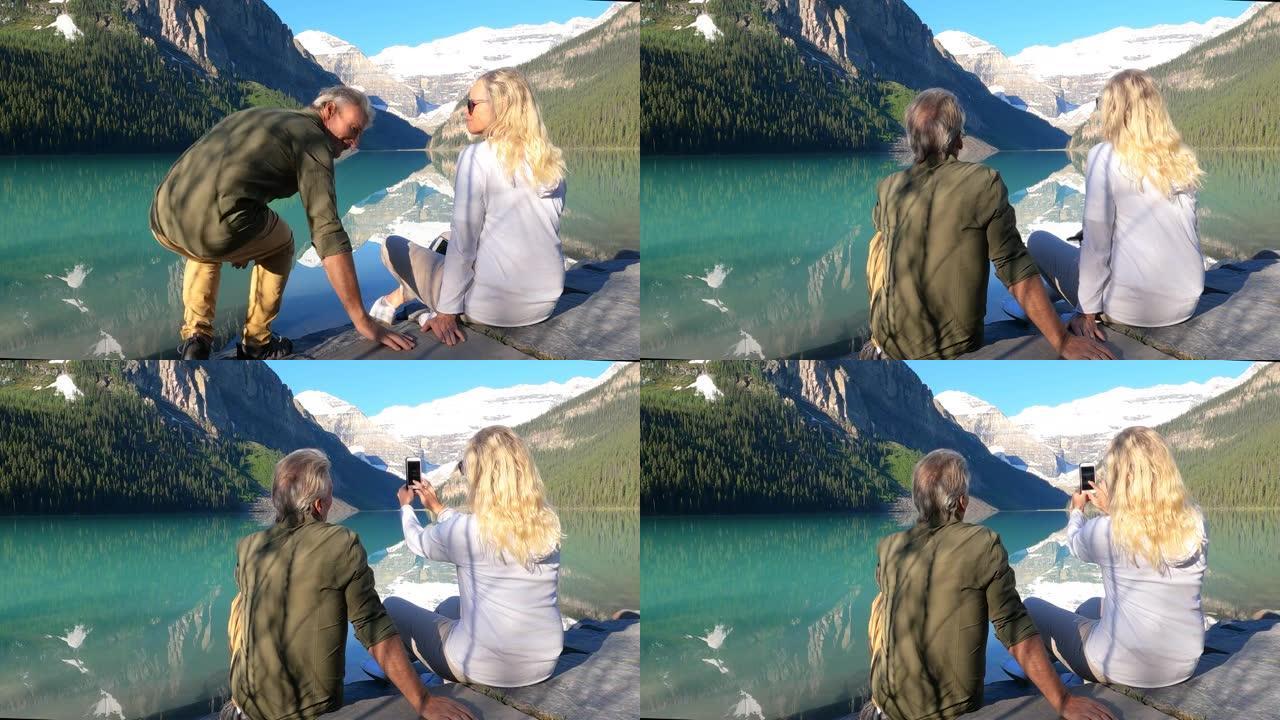 夫妇在湖岸山上放松，拍照并看着
