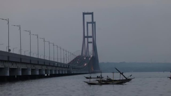 以苏拉马杜大桥为背景的爪哇海中通过的渔船。连接爪哇岛和马都拉岛的印度尼西亚最长的桥梁