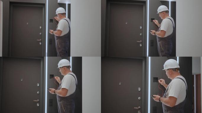 一名男电工用准备安装智能家居的电线测试仪检查网络中的电压。建筑工人修理带灯线的公寓