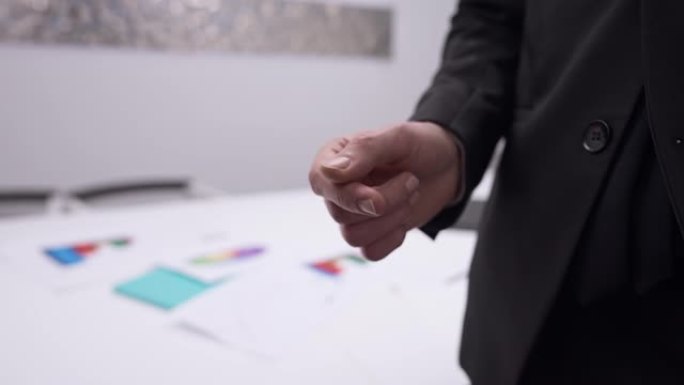 特写男性高加索人的手在慢动作和颤抖中传递名片。无法识别的合作伙伴在办公室室内交换联系。创业与合作。
