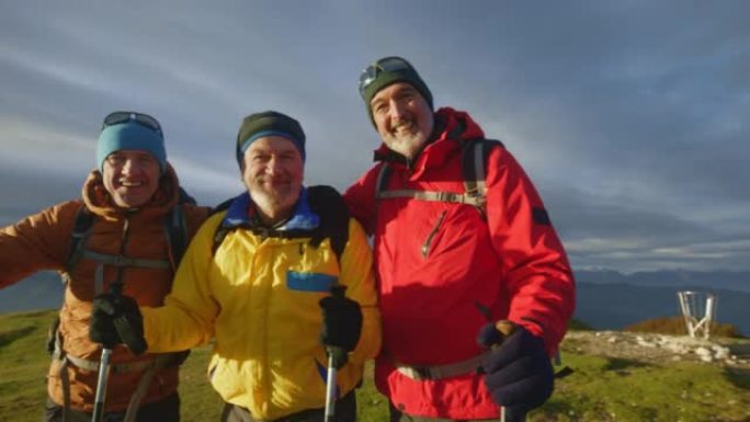 SLO MO三名高级男性徒步旅行者在日落时在山顶上摆姿势