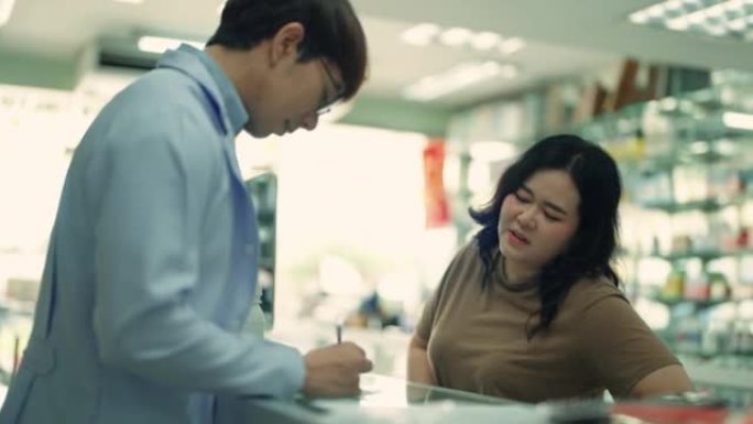 亚洲男性药剂师为女性患者提供药物建议并在药房中提出药物建议