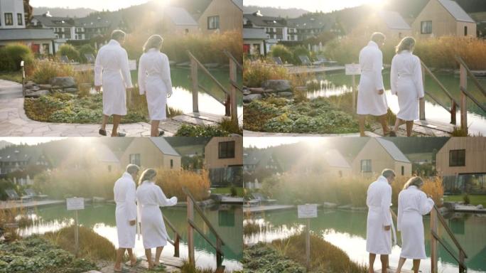 男人和女人穿着白色毛巾走向绿色池塘