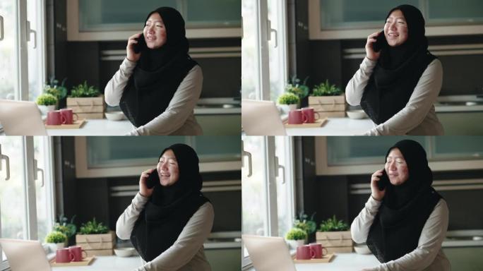 亚洲马来妇女在厨房用笔记本电脑戴头巾，白癜风皮肤状况