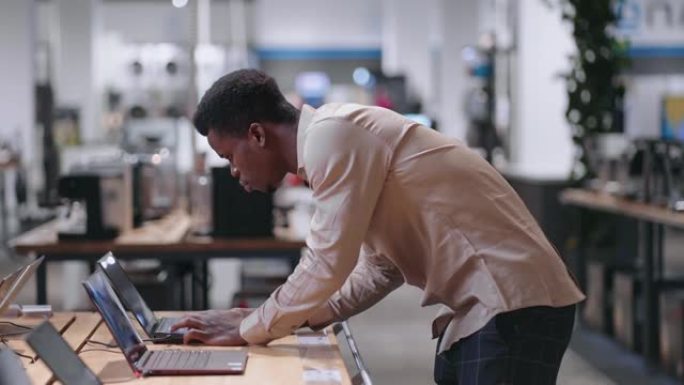 非洲裔美国人正在电子商店中选择笔记本电脑，在交易大厅观看展览样本