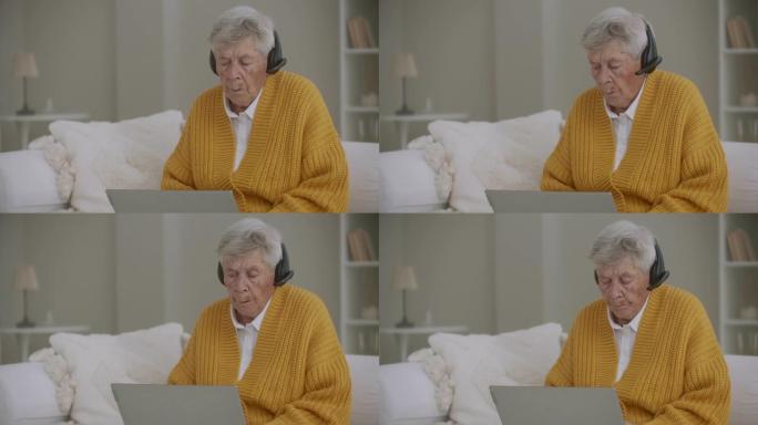 一位80多岁的老妇使用笔记本电脑和耳机进行视频通话。拨打热线电话