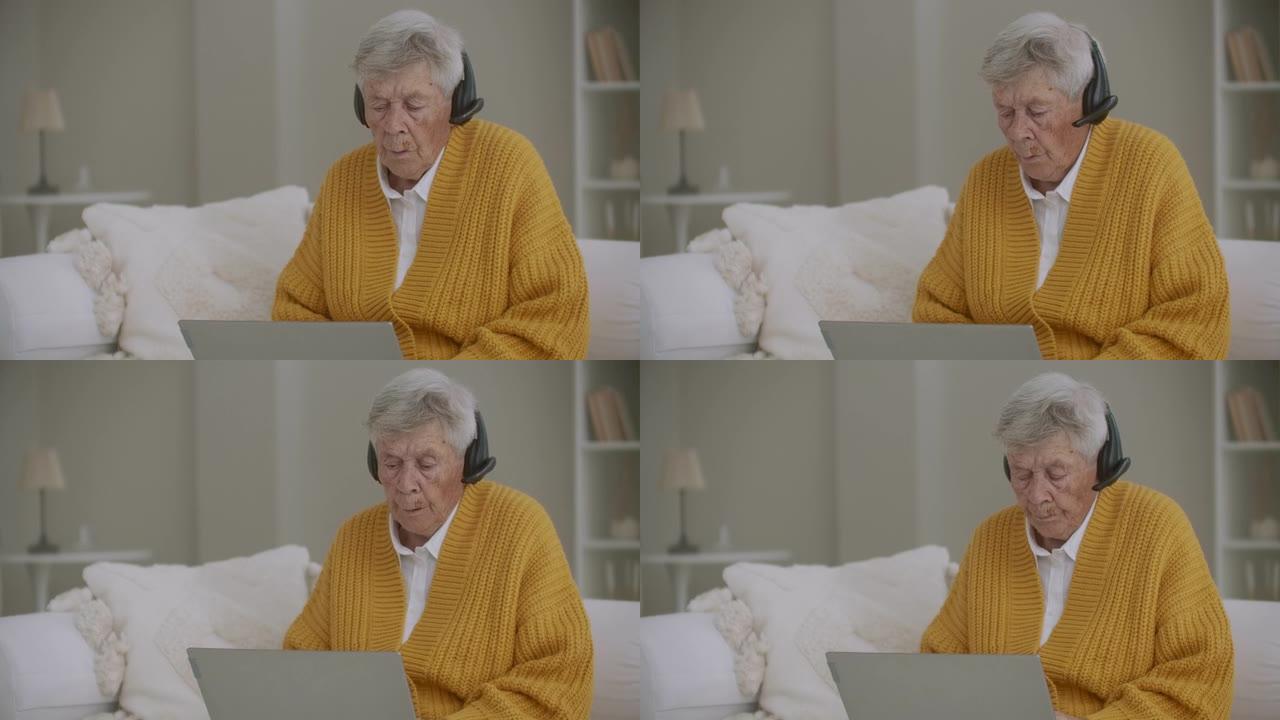一位80多岁的老妇使用笔记本电脑和耳机进行视频通话。拨打热线电话