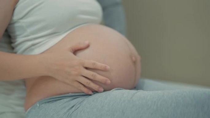 亚洲怀孕妇女温柔地抚摸和爱抚她的肚子