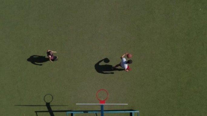 在绿色球场上打篮球的女孩和男人的俯视图