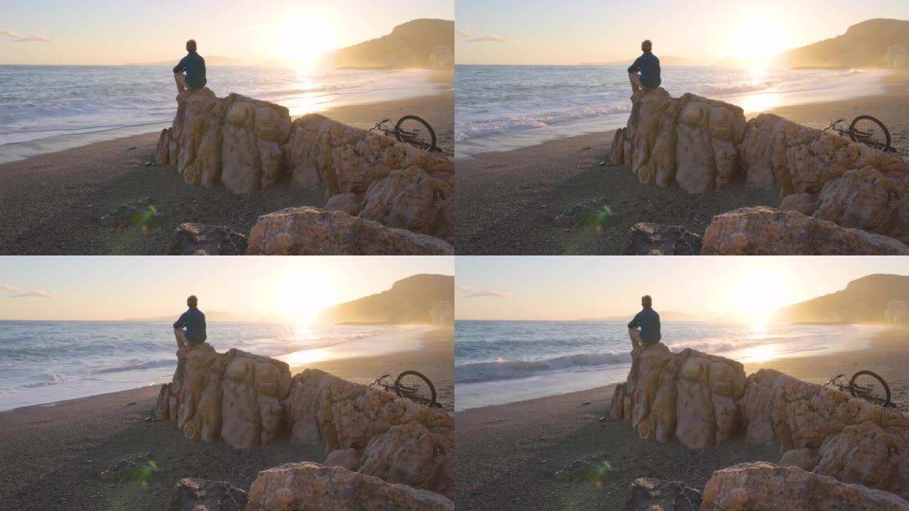 男子在海滩岩石上放松，向海望去