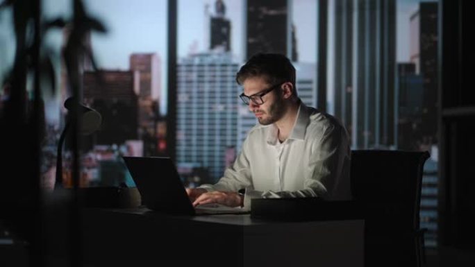 晚上在他的大城市办公室里，有思想的成功商人在笔记本电脑上工作的肖像。魅力型数字企业家为电子商务战略做