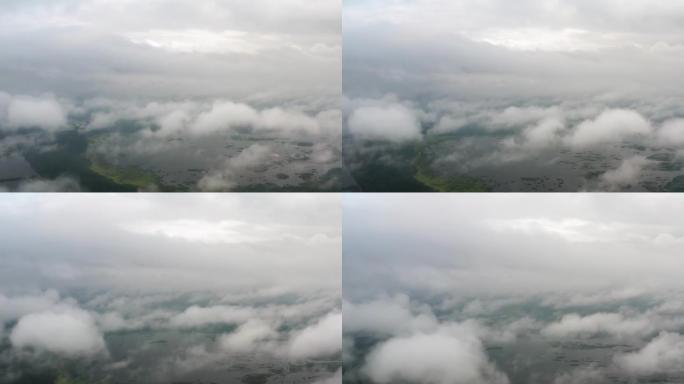 空中俯视无人机飞过蓬松的雨云，在美丽的湖边的绿色森林上滚动。从上面看松林有雾的早晨，多云，多雾的天气