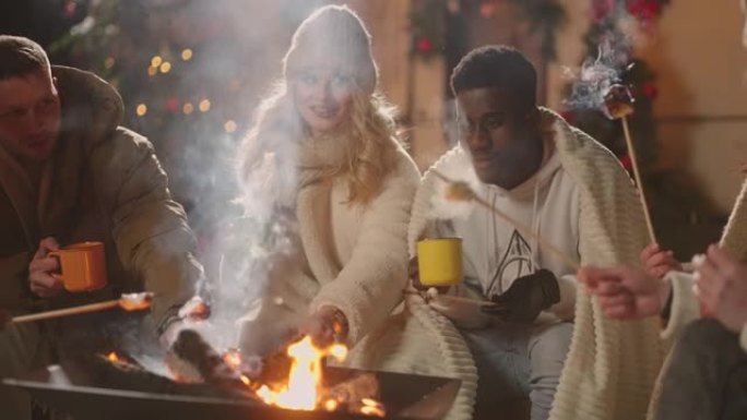 多民族爱心夫妇在朋友圈庆祝圣诞节，在篝火中烤棉花糖