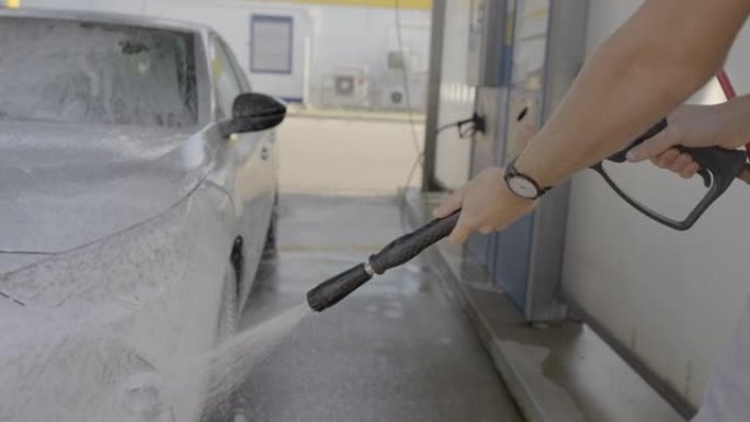 一名男子在洗车场用肥皂水洗车