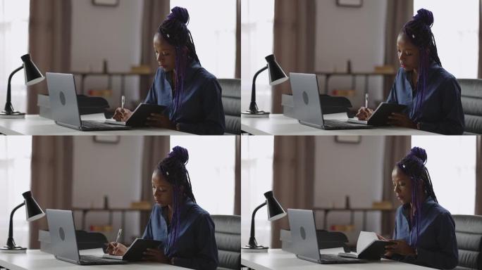 年轻的黑人妇女在家工作，在每天早上与老板和同事的在线商务会议上在笔记本上做笔记