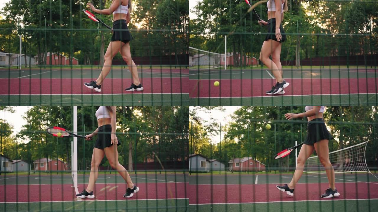 年轻的女网球运动员正在用球拍弹跳球，在腿上观看，女士在网球场上行走