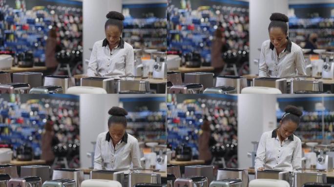 在家电商店购物，黑人女士正在看烤面包机，女人正在选择厨房和烹饪设备，