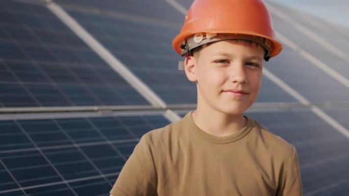 在太阳能发电厂戴着防护头盔的小男孩。儿童和绿色能量学的概念。清洁能源的孩子。在太阳能发电厂射击。生态