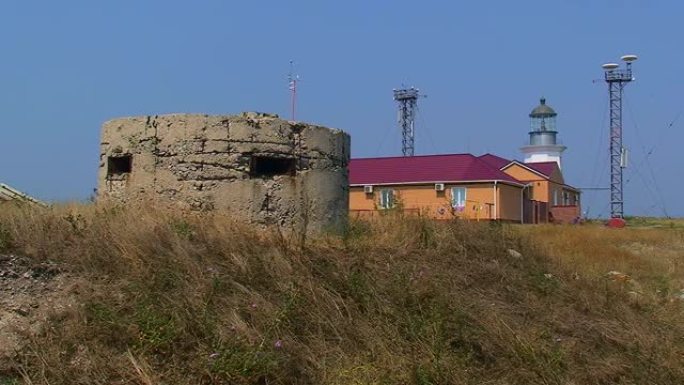 边境哨所大楼和灯塔背景下的旧掩体。