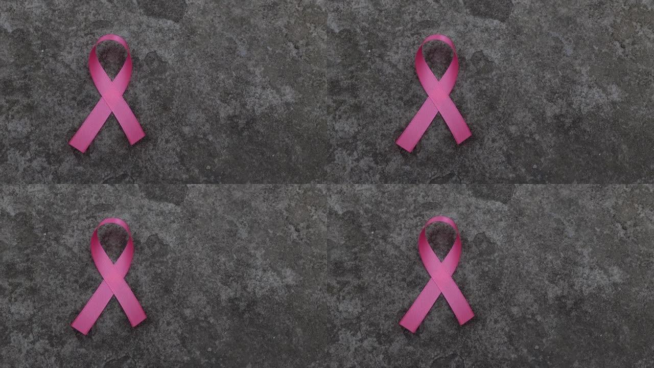 粉色丝带乳腺癌意识图标徽章放置在乡村水泥墙背景上。紫丝带世界癌症日，10月粉红日，全国癌症幸存者日概