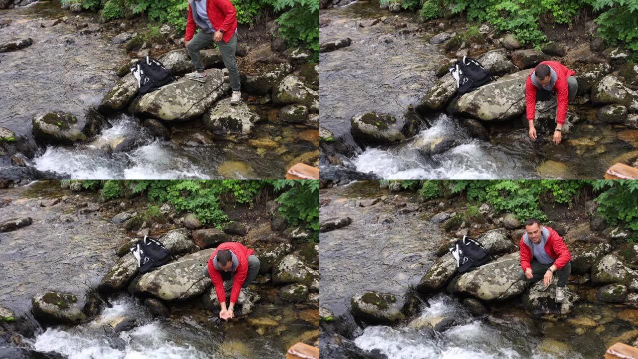 一个背着背包的游客从清澈的溪流中喝赋予生命的水。一个人喝一把的水。美丽的自然和山溪。