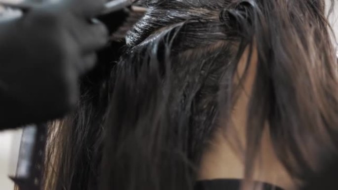 染发。染发剂。特写。调色师大师在沙龙或理发店用刷子染发女性黑发发根。