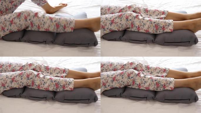 女人的腿躺在枕头上，以放松和预防静脉曲张